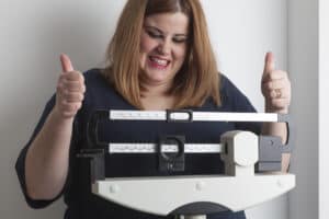 Woman-celebrating-weight-loss-on-a-medical-weight-scale-000082182281_Medium